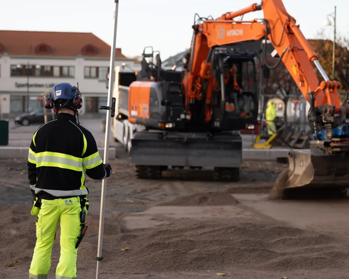 En byggnadsarbetare står framför en byggarbetsplats.